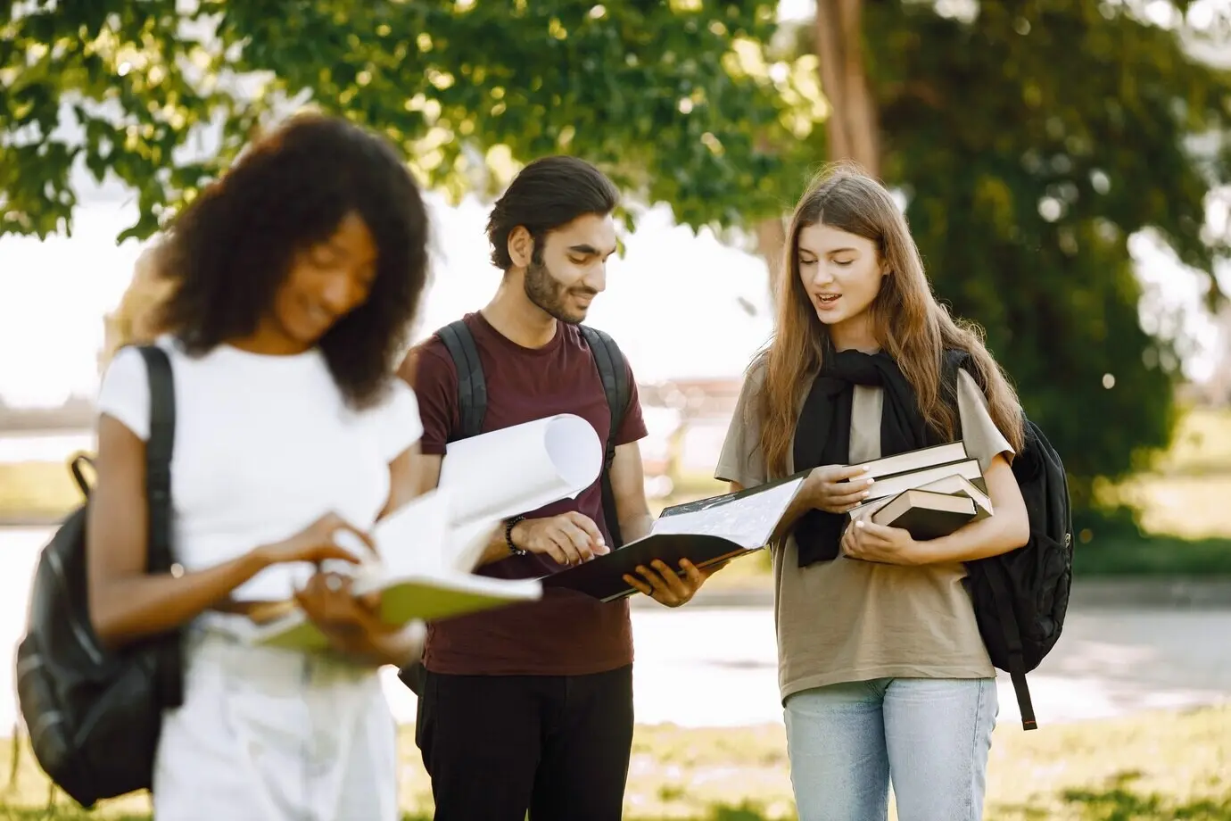 Ein unscharfes afrikanisches Mädchen steht abseits. Eine Gruppe internationaler Studierender steht zusammen im Park der Universität.
