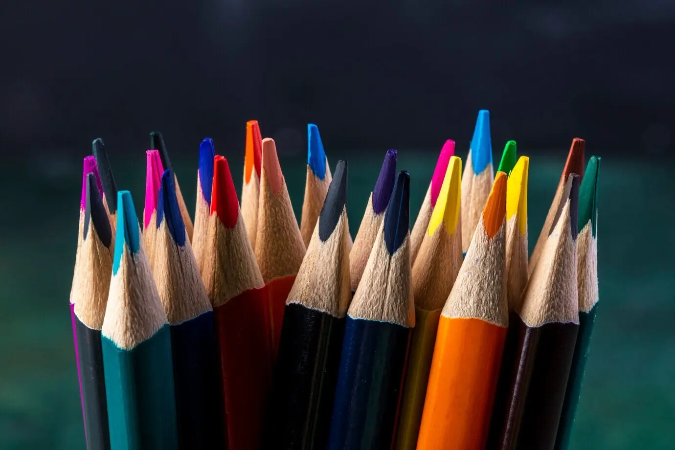 Seitenansicht eines Bündels von Buntstiften vor dunklem Hintergrund