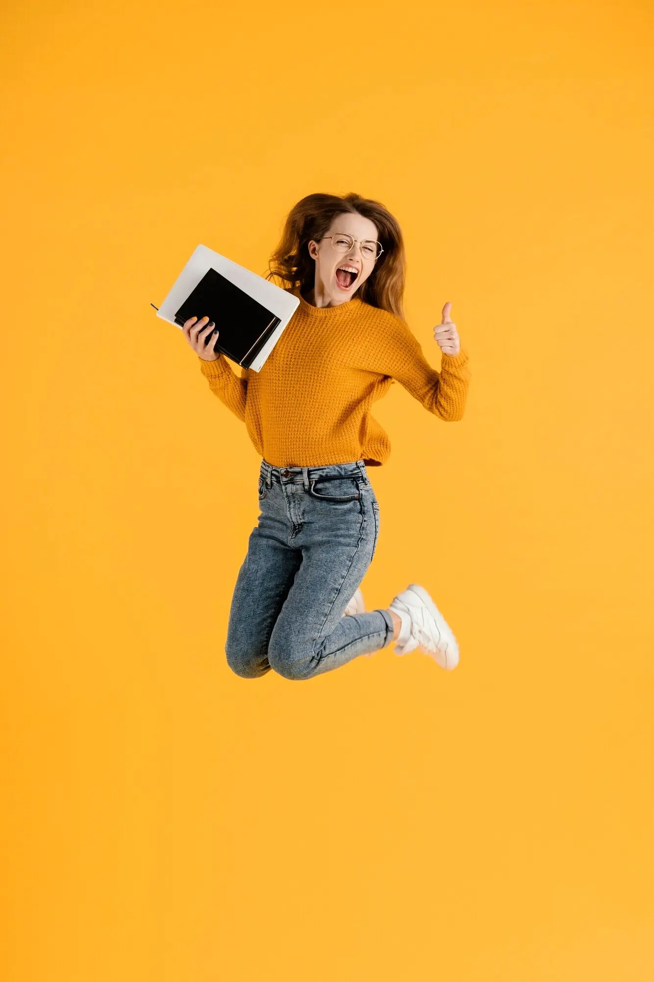 Porträt einer jungen Frau, die springt und Bücher hält.